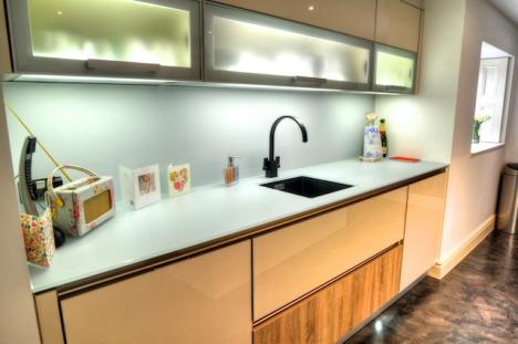 Undermount sink fitted to silk finish Lechner glass worktop, over storage units with high gloss jasmine and oak fronts.
