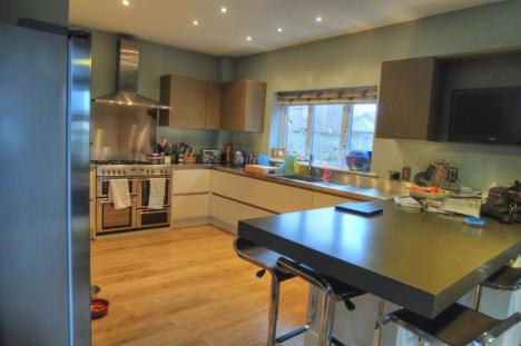 Handleless cream coloured Keller kitchen with steel worktops and Corian® breakfast bar peninsula