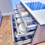 kitchen island with open drawers showing cutlery, crockery and pan storage under the hob