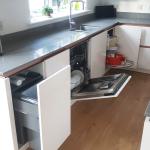 open kitchen units revealing integrated bins, dishwasher and carousel fitted under the sink run worktop
