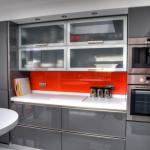 Grey gloss kitchen with orange splashbacks and Corian tops