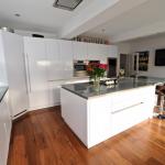 contemporary handleless white kitchen. Kitchen island with hob.