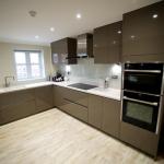 Handleless gloss fitted kitchen with Corian work surfaces and Amtico flooring.