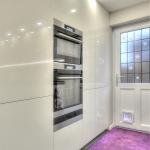 Keller handleless tall housings in gloss white with combination oven, oven and warming drawer.