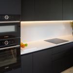 Bosch ovens in a tall housing next to a worktop run with induction hob and discreet extractor in the wall unit above