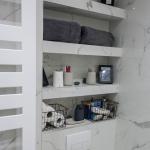 tiled shelves built into the recess above the WC with spare toilet rolls and personal items