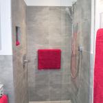 En-suite wet room enclosure tiled in grey porcelain with central floor drain, tiled niche and glass deflector screen