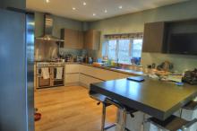Handleless cream coloured Keller kitchen with steel worktops and Corian® breakfast bar peninsula