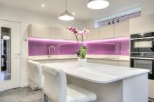 White high gloss handleless Keller kitchen with pink glass splashbacks.